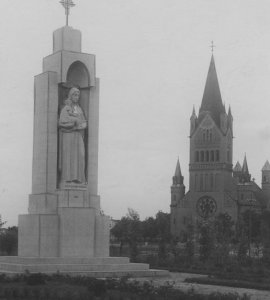 Widok ogólny figury i kościoła Zwiastowania Najświętszej Maryi Panny w tle.  - Fotografia wykonana w latach 1918 - 1937.