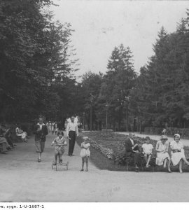 Fragment parku zdrojowego w Inowrocławiu - Fragment parku zdrojowego w Inowrocławiu, w którym wypoczywają spacerowicze. Widoczne dziecko na trójkołowym rowerze. Fotografia wykonana w latach 1918 - 1937.